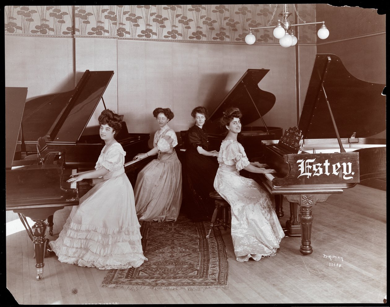 1908年Estey钢琴公司的四名女性坐在钢琴上（银色明胶印刷） 作者 拜伦公司