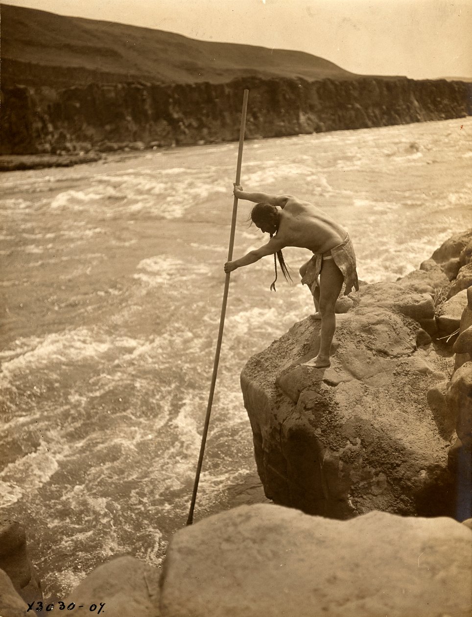 特拉克卢伊特印第安人，站在岩石上，用浸网捕鱼，约 1910 年（黑白照片） 作者 爱德华警长柯蒂斯