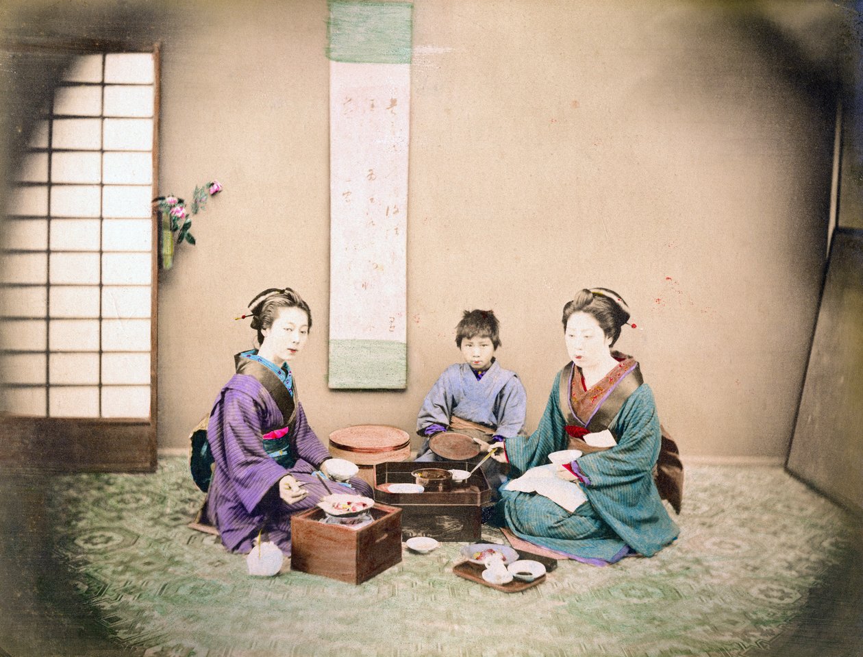 约 1890 年，两名妇女和一名儿童坐在垫子上共进午餐（手绘彩色照片） 作者 日本摄影师