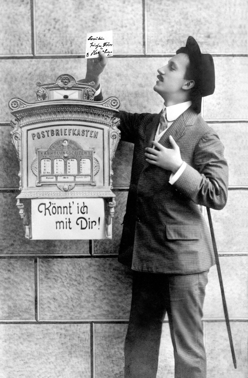 An elegant man in a suit, hat and cane, posts a note in a mailbox. Germany around 1920 Historic photograph, man next to a letterbox, around 1920 作者 不明