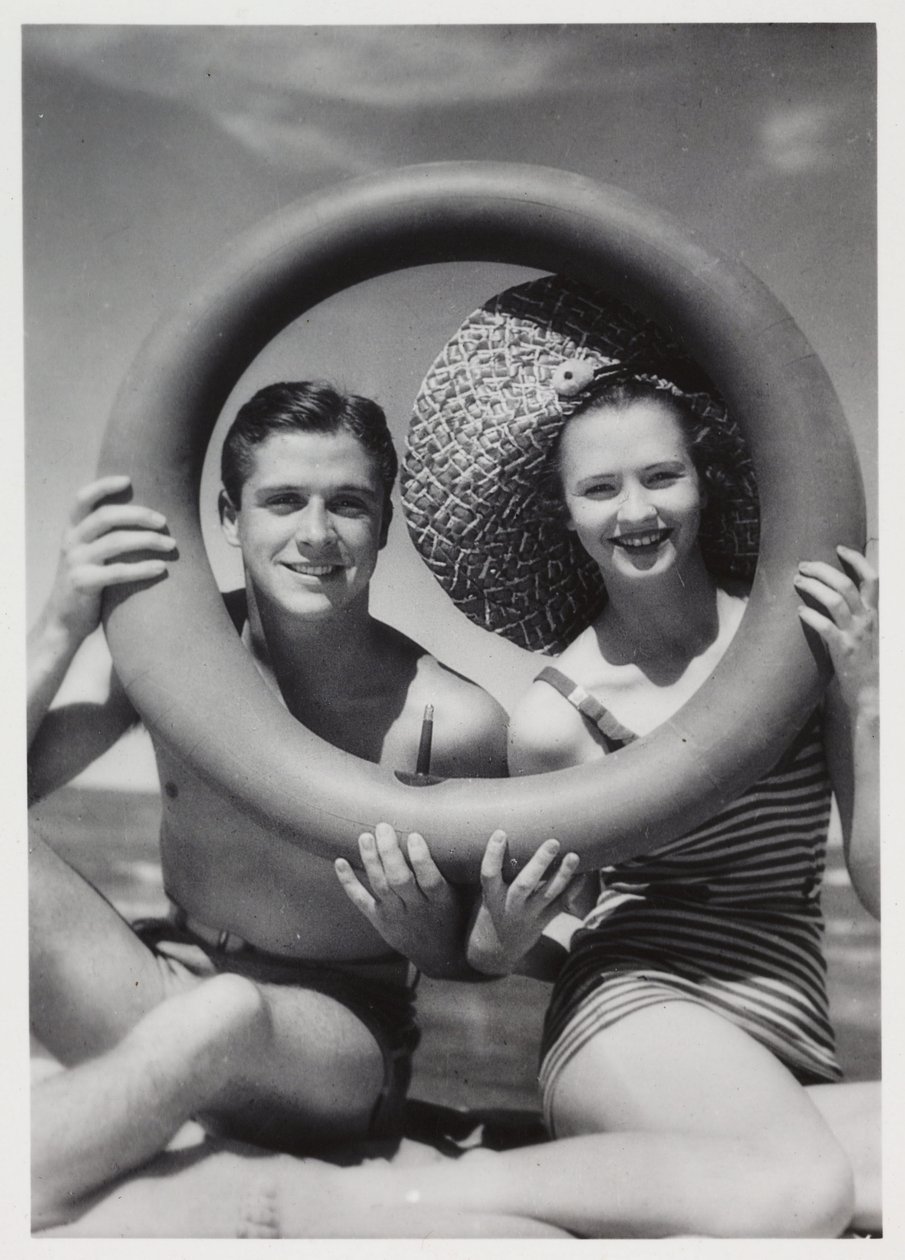 Man and woman looking through a rubber ring on beach, c 1935 作者 不明
