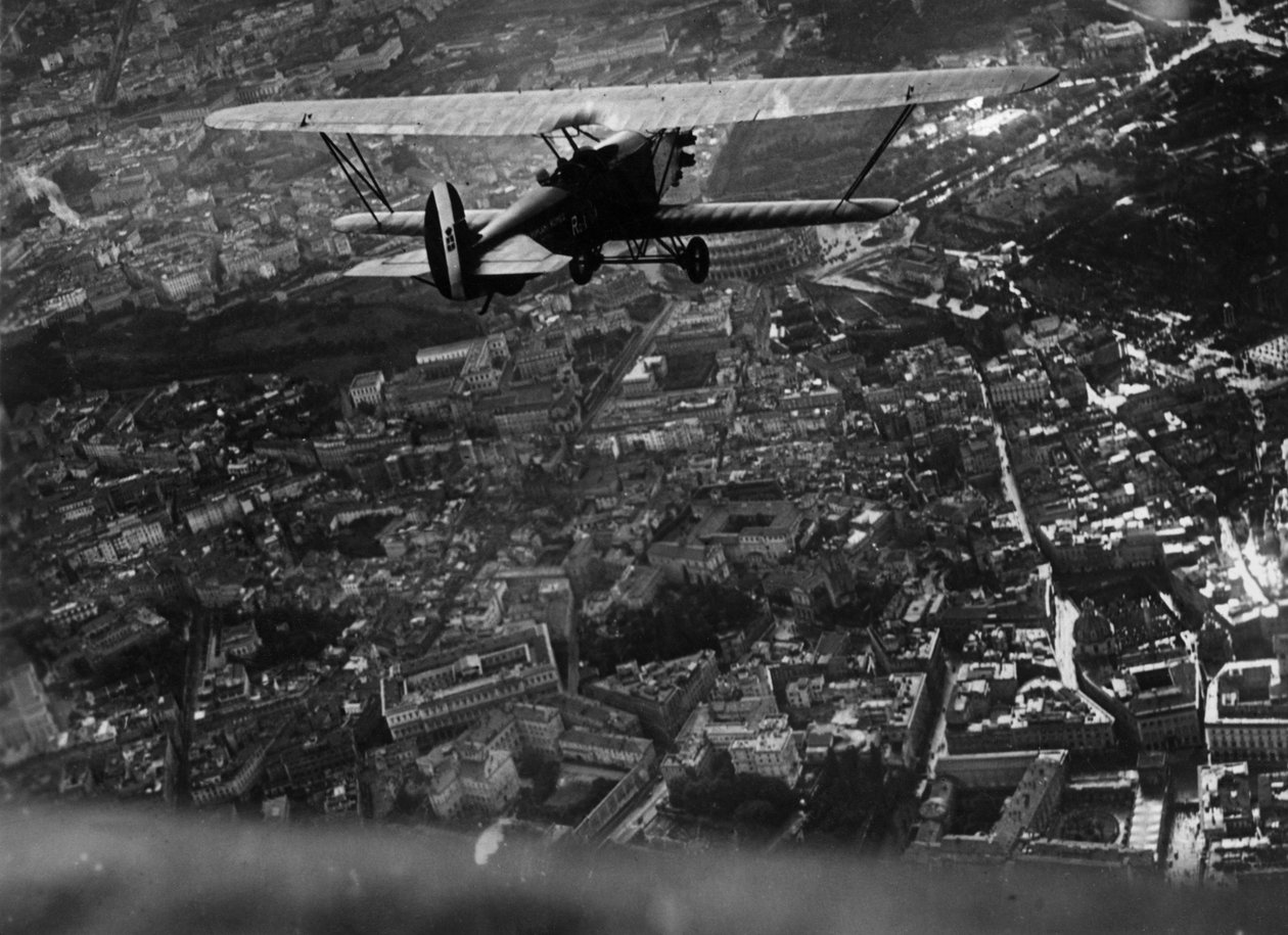 罗马（意大利），约1930年。意大利航空部长伊塔洛-巴尔博（1896-1940）在为旅游沙龙开幕而进行的空中表演中，乘坐 "Ro1 "双翼飞机飞越城市上空 - 意大利罗马，约1930年。意大利航空部长 作者 未知艺术家