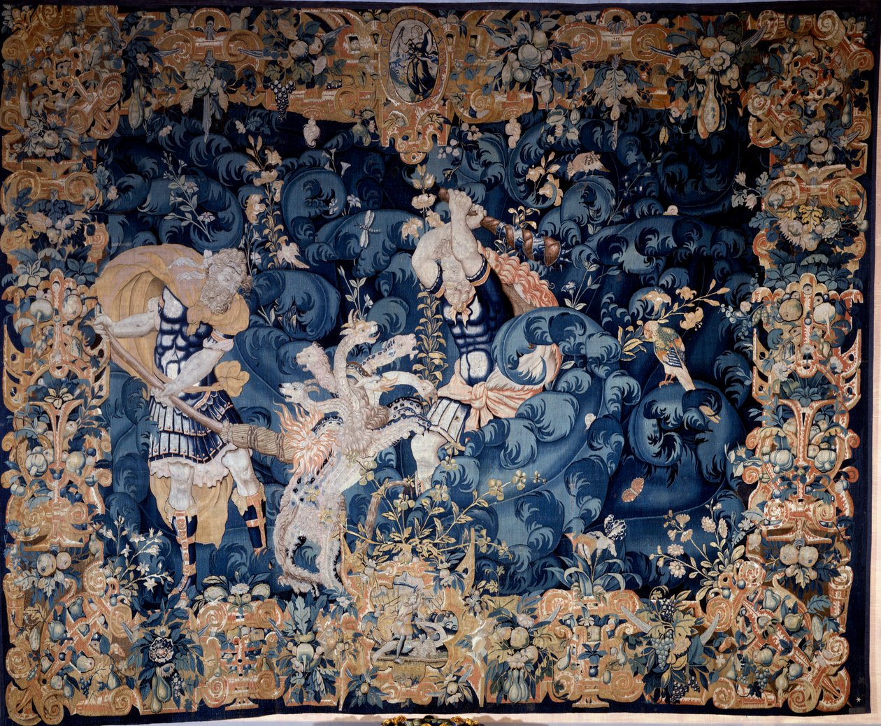 赫拉克勒斯击落了勒恩的九头蛇，它燃烧了他的仆人 Iolas Tapestry 的羊毛和丝绸，匿名，16 世纪后期。 看，文艺复兴国家博物馆。 作者 未知艺术家