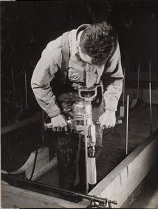 [男子使用手持机器加工木头]