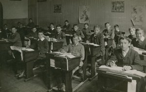 坐在他们的书桌后的男性学生在教训期间在学校 作者 英国摄影师