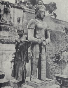 Young Buddhist novice monk beside a statue of the Buddha, French Indochina (b/w photo)