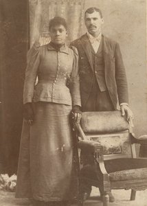 一对非洲裔美国人夫妇站在椅子后面的照片，约1890年。 作者 施密茨工作室