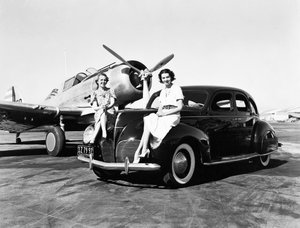 加利福尼亚州: 1939年 两名妇女在机场坐在一辆1939年林肯Zephyr轿车的挡泥板上，后面停着一架单引擎飞机（黑白照片 作者 不明