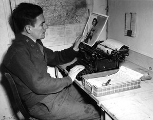第二次世界大战（1939-1945） - 第二次世界大战（二战或二战）：穆齐格（阿尔萨斯）法国 1944 年 12 月 1 日：Beachead News（GI 的新闻杂志）的下士 Flanerty 编年史在看他发表的海报照片 下一期报纸。 作者 不明