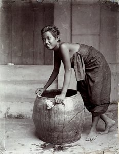面带微笑的泰国年轻女子，推着一个大集装箱 作者 未知的摄影师