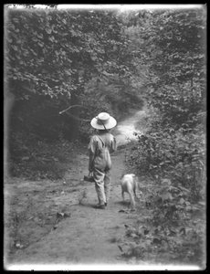 1911年8月20日威廉·格雷·哈斯勒戴着草帽和工作服，带着钓鱼竿和篮子，带着小狗在树林里散步（Bessie） 作者 威廉·戴维斯·哈斯勒