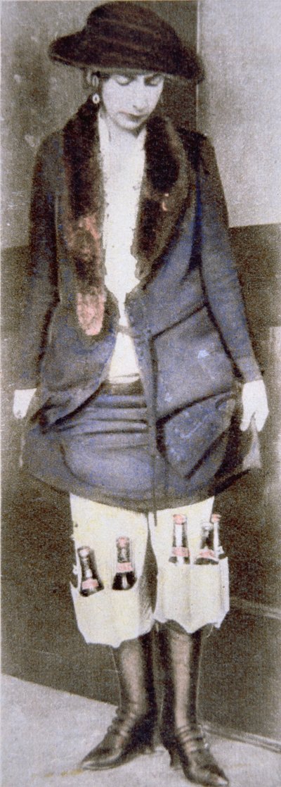 美国禁酒令期间（1920年至1933年），一名妇女将非法啤酒瓶藏在裙子下面的特殊内衣口袋里（彩色照片）。 作者 美国摄影师
