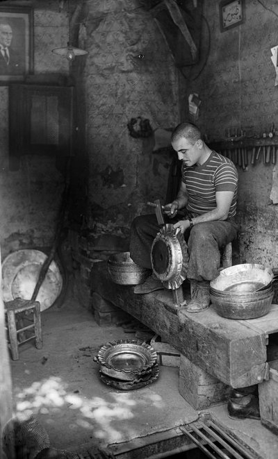 意大利金属工匠在金属板上锤打制作凸起的器皿或壶，意大利 作者 伯纳德·罗杰斯