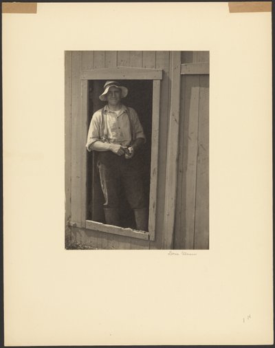 [一个戴草帽的男人站在谷仓门口 手里拿着烟袋] 作者 多丽丝·乌尔曼（Doris Ulmann）