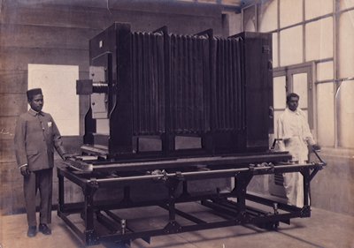 两名印度助理站在印度测量局摄影部的大型照相机旁，约 1911 年（照片） 作者 英国摄影师