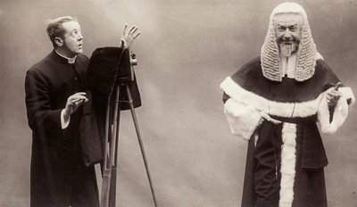 A man in a cassock aims the lens of his camera at a man dressed like a pope 作者 旋转摄影有限公司