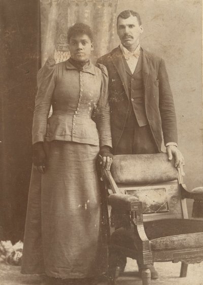 一对非洲裔美国人夫妇站在椅子后面的照片，约1890年。 作者 施密茨工作室