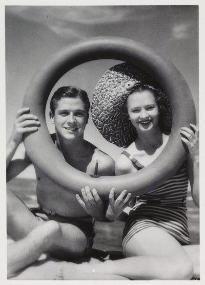 Man and woman looking through a rubber ring on beach, c 1935 作者 不明