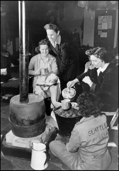 第二次世界大战（1939-1945年）：在一个英国空军基地，WAC（女子陆军团）的一支部队被关在那里，她们中的一群人围着她们的小木屋的炉子吃点心。摄影 1943年。 作者 不明