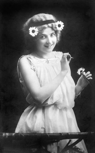 女人从花上扯下花瓣："他爱我。他不喜欢我。他爱我......"1912年左右的摄影作品 作者 不明