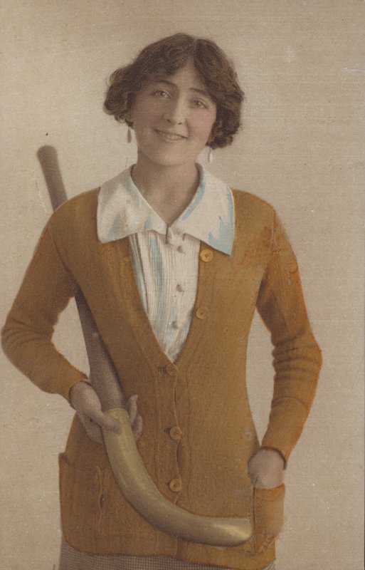 Pretty girl, in knitted jumper, with pearl earrings, holding hockey stick (photo) 作者 英国摄影师